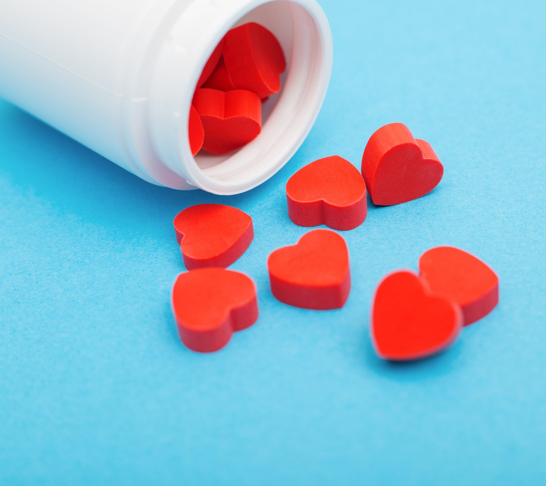 Red,Heart,Shaped,Pills,With,Plastic,Bottle,On,Blue,Background.concept